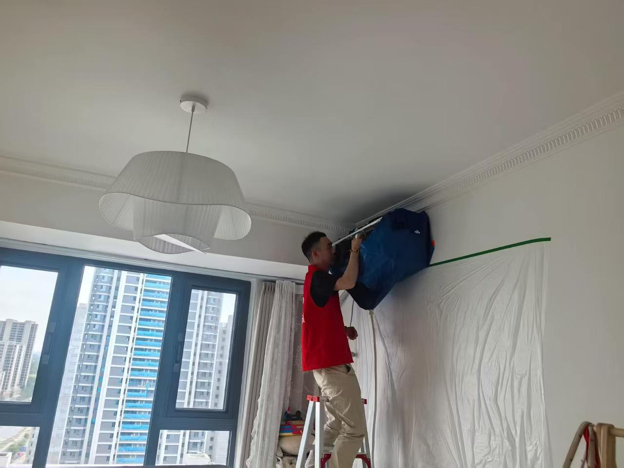阜阳港龙置业工作人员在业主家室内安装空调，墙面已做防护