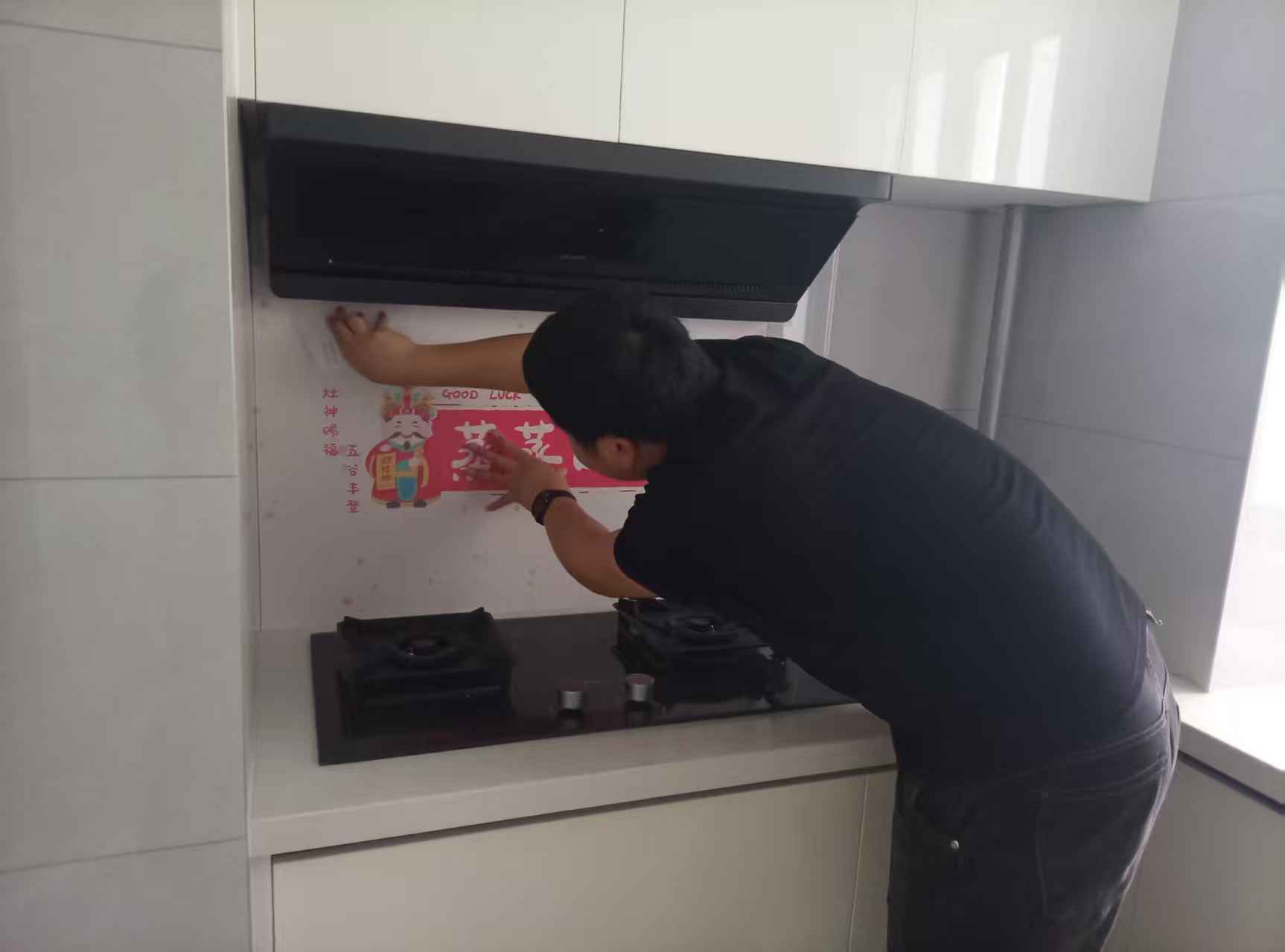 阜阳港龙置业工作人员为新房厨房张贴灶神装饰贴